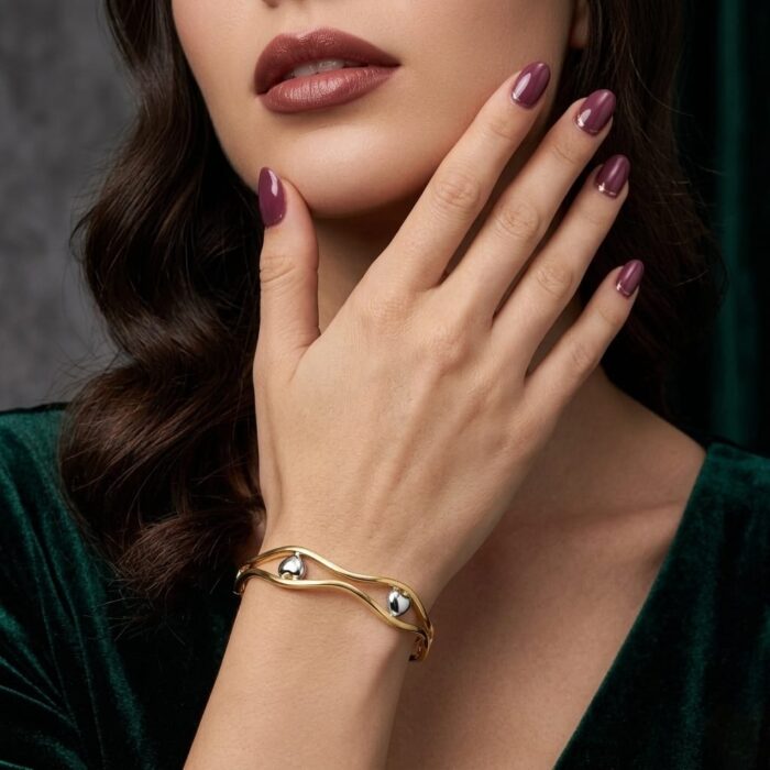⁦اسورة فاخرة باللون الذهبي الأنيق، بتصميم مموج ومزدوج، تتزين بقلوب رقيقة باللون الفضي اللامع. قطعة عصرية تضفي جاذبية لإطلالتك.⁩ - الصورة ⁦3⁩