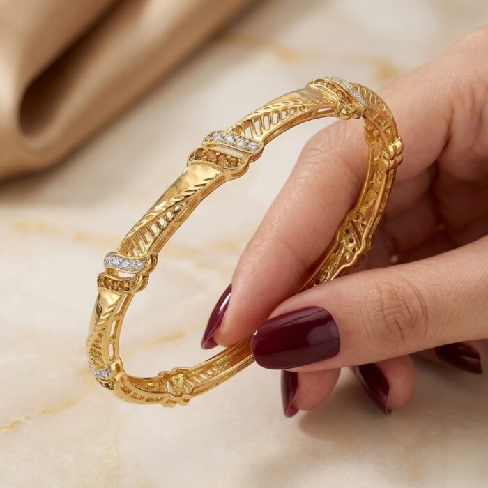 ⁦اسورة فاخرة باللون الذهبي، بتصميم أنيق ومفرغ، تُزينها فصوص زركون دقيقة براقة بلمسات متداخلة، تمنح إطلالتك فخامة عصرية متقنة التفاصيل.⁩ - الصورة ⁦4⁩
